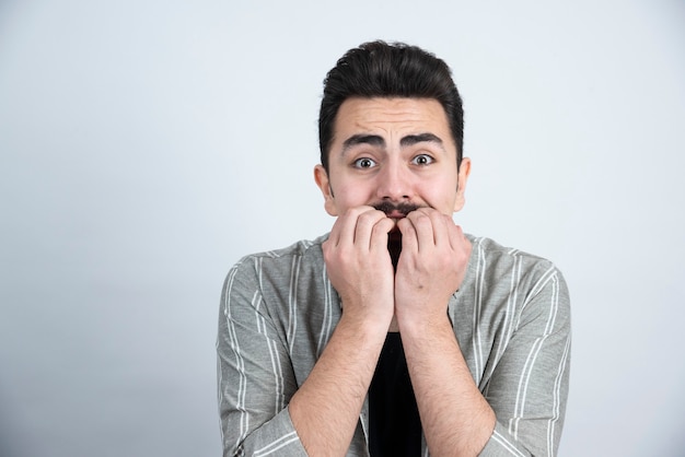 Retrato de joven guapo en ropa casual de pie y mirando sorprendido.