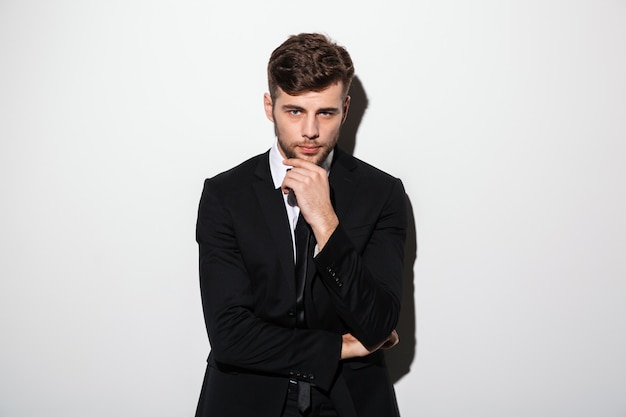 Retrato de joven guapo en traje negro con la barbilla