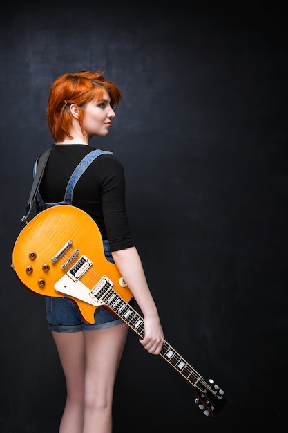 Foto gratuita retrato de joven con guitarra sobre fondo negro.