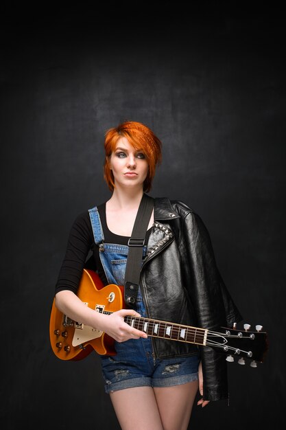 Retrato de joven con guitarra sobre fondo negro.