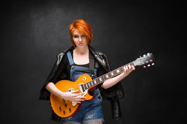 Retrato de joven con guitarra sobre fondo negro.