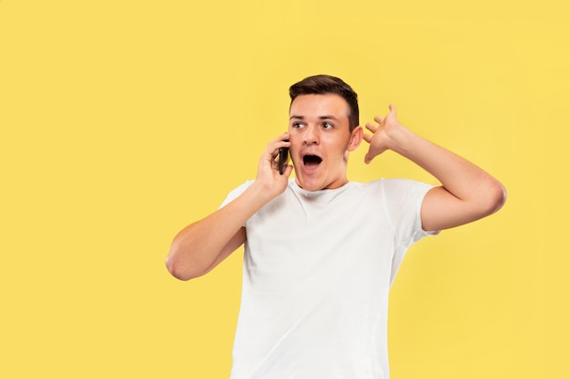 Retrato de joven hablando por teléfono aislado en la pared amarilla