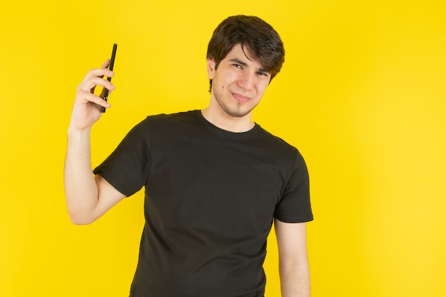 Retrato de un joven hablando por teléfono móvil contra amarillo.