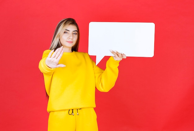 Retrato de joven hermosa celebración de marco de voz en blanco en la pared roja