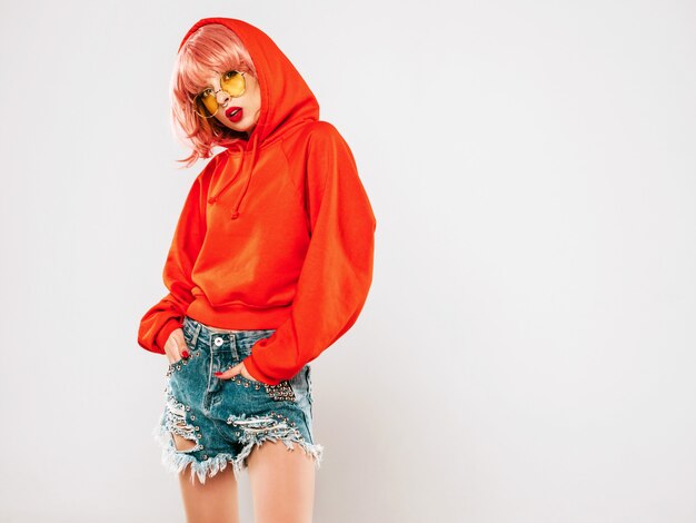 Retrato de joven hermosa chica mala hipster en moda verano rojo con capucha y arete en la nariz. Modelo positivo de verano en peluca