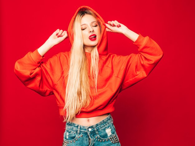 Retrato de joven hermosa chica mala inconformista en sudadera con capucha roja de moda y arete en la nariz. Modelo positivo