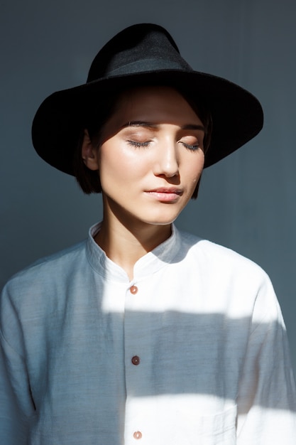 Retrato de joven hermosa chica morena con sombrero negro.