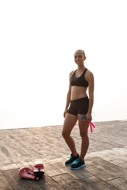 Retrato de joven hermosa deportiva preparándose para el entrenamiento de boxeo en la playa.