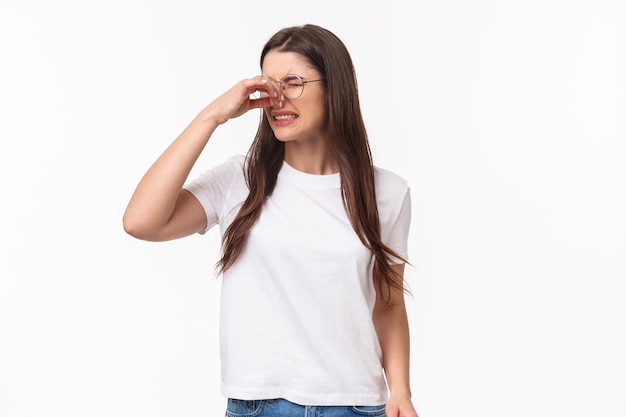 Retrato de joven hermosa disgustada y disgustada con gafas, cerrar la nariz