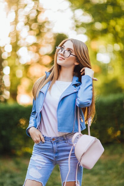 Retrato de una joven hermosa en gafas en jeans con pantalones elegantes