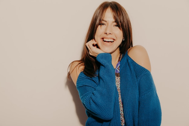 Retrato de joven hermosa muchacha sonriente hipster en ropa de moda de verano. Mujer despreocupada atractiva que presenta cerca de la pared en estudio. Modelo positivo divirtiéndose