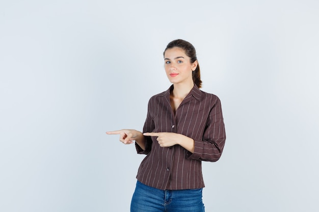 Retrato de joven hermosa mujer apuntando a la izquierda en la chaqueta y mirando alegre vista frontal