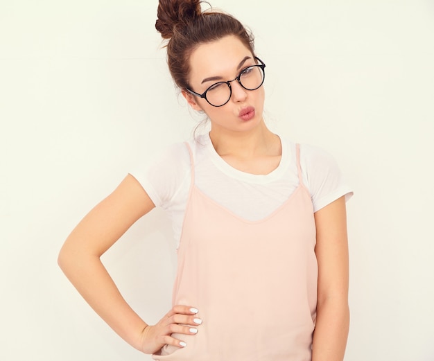 Retrato de joven hermosa mujer morena modelo chica con maquillaje desnudo en ropa de verano colorido hipster rosa posando junto a la pared. Dando beso de aire y guiñando un ojo