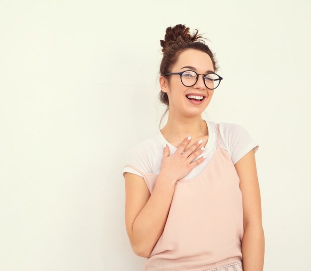 Retrato de joven hermosa mujer morena modelo chica con maquillaje desnudo en ropa de verano colorido hipster rosa posando junto a la pared. mirando felizmente