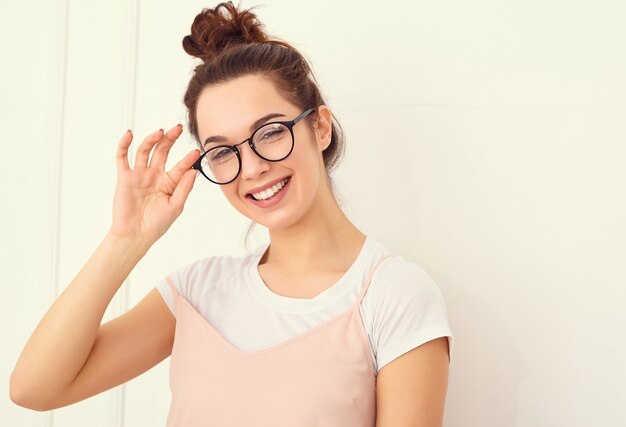 Retrato de joven hermosa mujer morena modelo chica con maquillaje desnudo en ropa de verano colorido hipster rosa posando junto a la pared. mirando felizmente