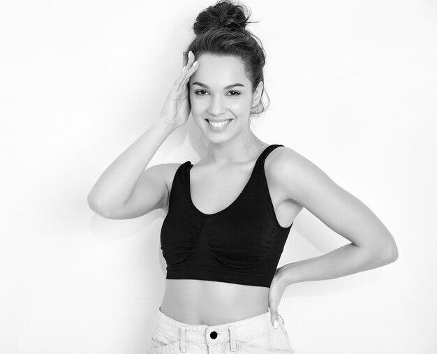 Retrato de joven hermosa mujer morena modelo chica con maquillaje desnudo en verano camiseta top y jeans ropa posando junto a la pared.