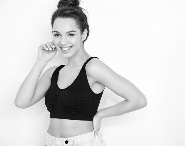 Retrato de joven hermosa mujer morena modelo chica con maquillaje desnudo en verano camiseta top y jeans ropa posando junto a la pared.