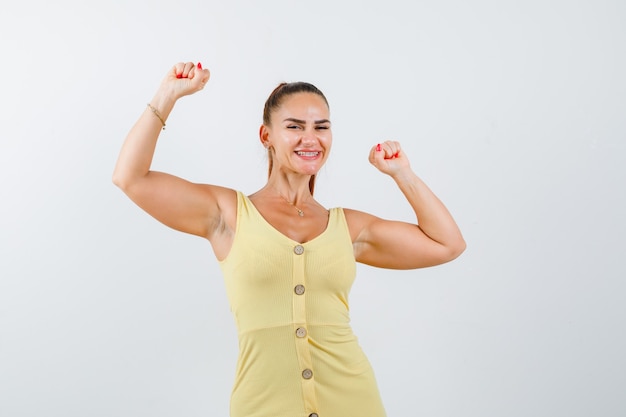 Foto gratuita retrato de joven hermosa mujer mostrando gesto ganador en vestido y mirando orgullosa vista frontal