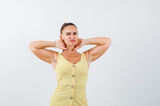 Foto gratuita retrato de joven hermosa mujer que sufre de dolor de cuello en el vestido y que mira la vista frontal enferma