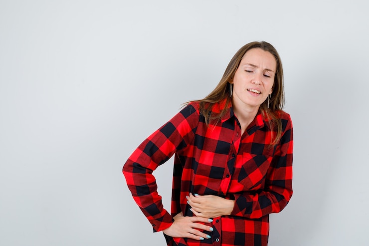 Foto gratuito retrato de joven hermosa mujer que sufre de dolor de estómago en camisa casual y mirando hacia adelante mal