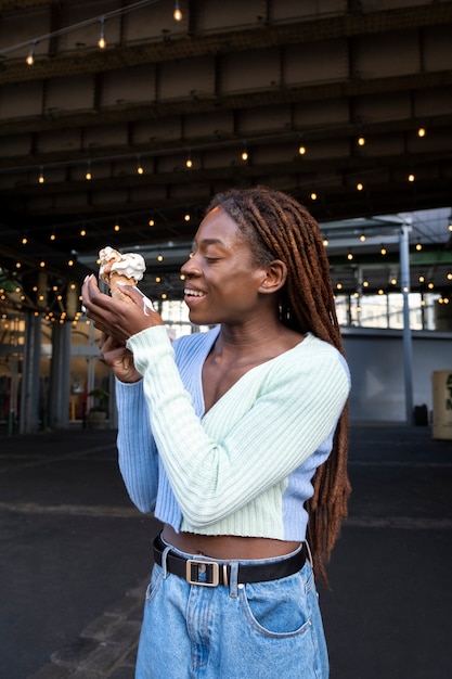 Retrato de una joven hermosa mujer con rastas afro disfrutando de un helado en la ciudad