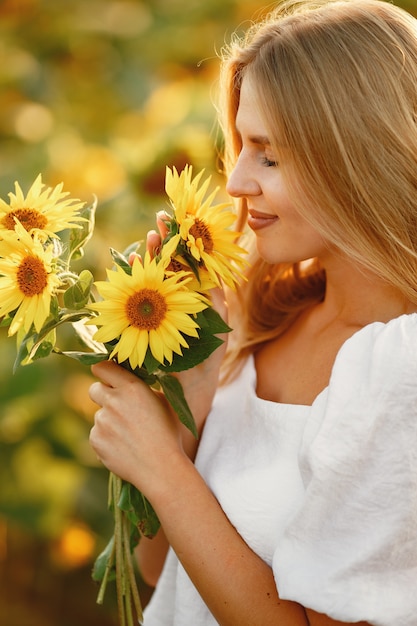 Retrato de joven hermosa mujer rubia en campo de girasoles en luz trasera. Concepto de campo de verano Mujer y girasoles. Luz de verano. Belleza al aire libre.