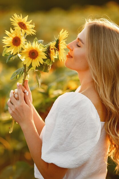 Retrato de joven hermosa mujer rubia en campo de girasoles en luz trasera. Concepto de campo de verano Mujer y girasoles. Luz de verano. Belleza al aire libre.