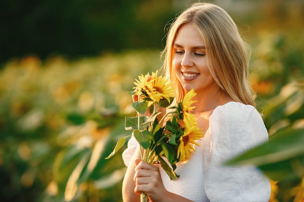 Retrato de joven hermosa mujer rubia en campo de girasoles en luz trasera. Concepto de campo de verano Mujer y girasoles. Luz de verano. Belleza al aire libre.