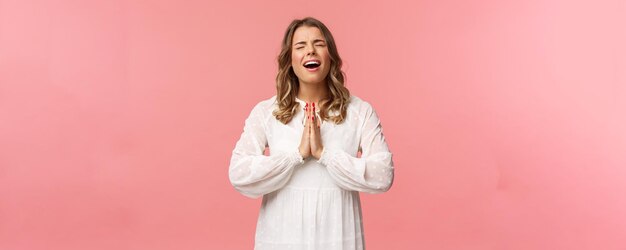 Retrato de una joven y hermosa mujer rubia esperanzada y desesperada vestida de blanco quejándose quejándose de una vida cruel rezando a Dios que el sueño se haga realidad llorando con el corazón durante la súplica pide por favor