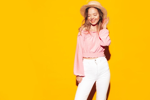 Retrato de joven hermosa mujer rubia sonriente en ropa de verano de moda mujer despreocupada posando cerca de la pared amarilla en el estudio Modelo positivo divirtiéndose en el interior Alegre y feliz Con sombrero