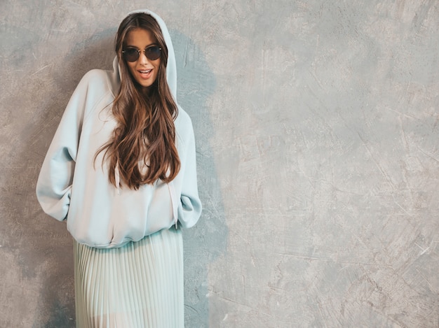 Retrato de joven hermosa mujer sonriente mirando. Chica de moda en ropa casual de verano con capucha y falda.