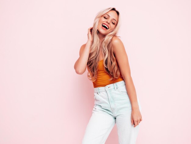 Retrato de joven hermosa mujer sonriente en ropa de verano de moda Mujer rubia despreocupada sexy posando junto a la pared rosa en el estudio Modelo positivo divirtiéndose en el interior Alegre y feliz