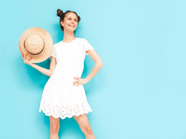 Retrato de joven hermosa mujer sonriente en vestido de verano de moda mujer despreocupada posando cerca de la pared azul en el estudio Modelo positivo divirtiéndose en el interior Alegre y feliz Con sombrero