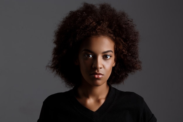 Retrato de joven hermosa niña africana sobre pared oscura