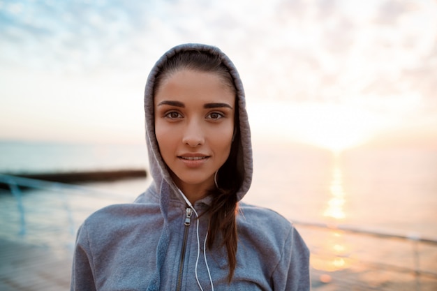 Retrato de joven hermosa niña deportiva al amanecer sobre el mar.