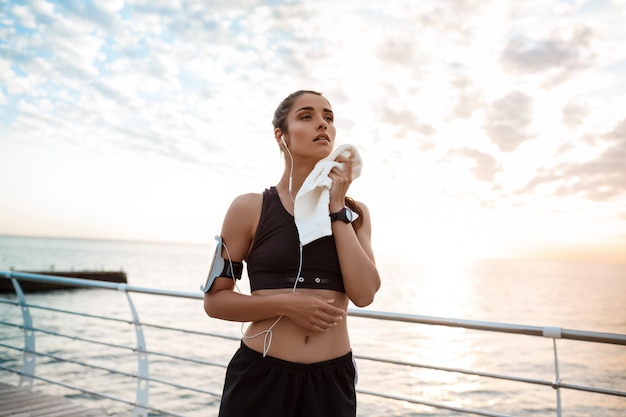 Retrato de joven hermosa niña deportiva al amanecer sobre el mar.