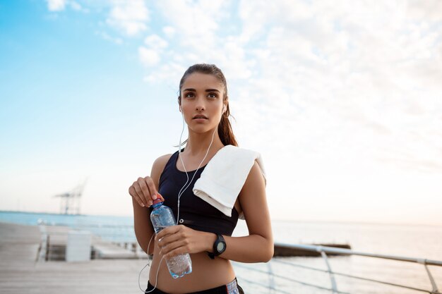 Retrato de joven hermosa niña deportiva al amanecer sobre el mar.