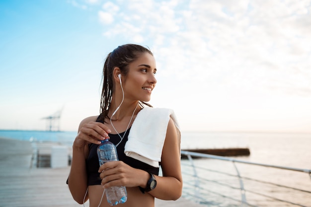 Retrato de joven hermosa niña deportiva al amanecer sobre el mar.