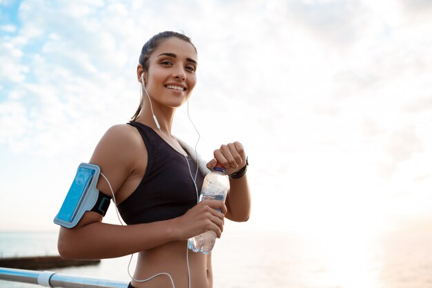 Retrato de joven hermosa niña deportiva al amanecer sobre el mar.