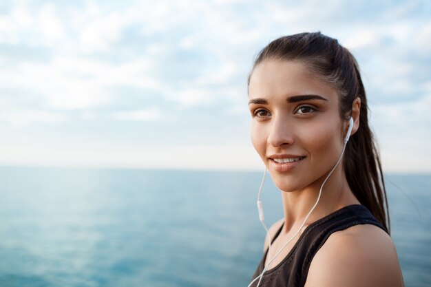 Retrato de joven hermosa niña deportiva al amanecer sobre el mar.