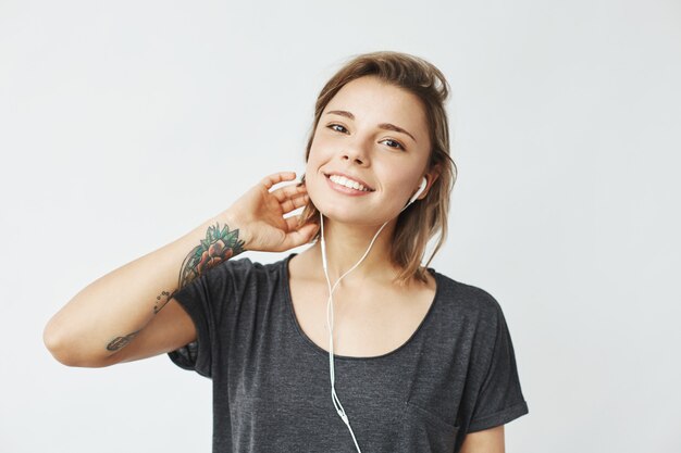 Retrato de joven hermosa niña feliz escuchando música sonriente en auriculares.