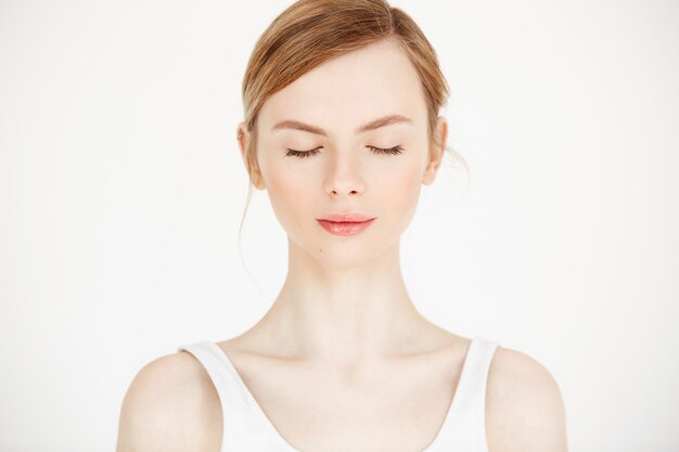 Retrato de joven hermosa con la piel limpia y fresca aislada sobre fondo blanco. Ojos cerrados. Estilo de vida de belleza y salud.