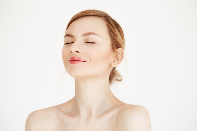 Retrato de joven hermosa con la piel limpia y fresca aislada sobre fondo blanco. Ojos cerrados. Estilo de vida de belleza y salud.