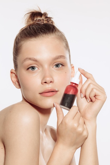 Retrato de una joven hermosa con un producto de belleza facial cuidando la piel aislada sobre el fondo blanco del estudio