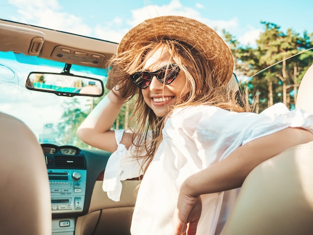 Retrato de joven hermosa y sonriente hipster en coche descapotable