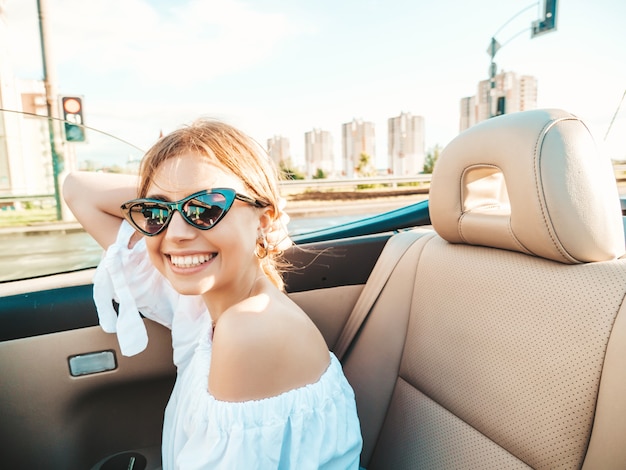 Retrato de joven hermosa y sonriente mujer hipster en coche descapotable