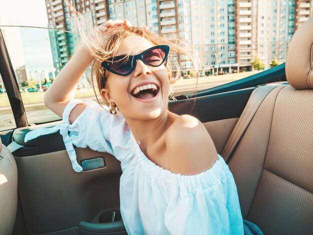Retrato de joven hermosa y sonriente mujer hipster en coche descapotable