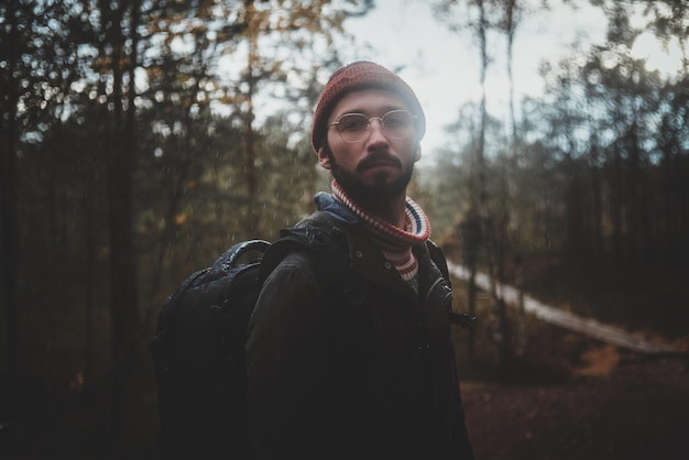Retrato de joven hipster barbudo con mochila en el bosque de otoño.