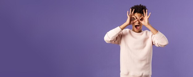 Retrato de un joven hispano divertido y entusiasta que se engaña haciendo máscaras de anteojos con han