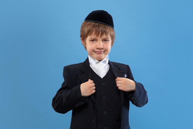 Retrato de un joven judío ortodoxo aislado en estudio azul